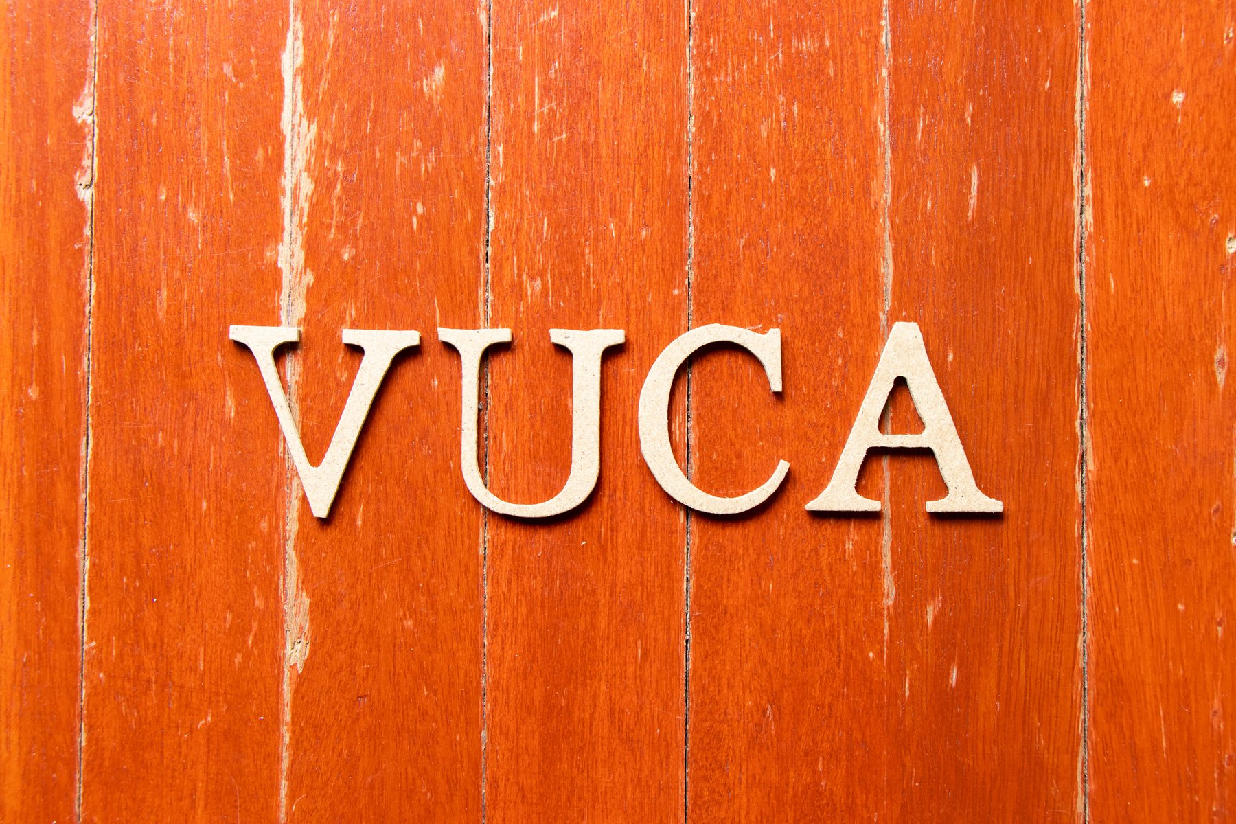 Alphabet letter in word VUCA (abbreviation of Volatility, uncertainty, complexity and ambiguity) on old red color wood plate background